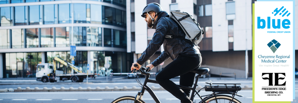 A person biking on a city street with a overlay on the side showing Blue Federal Credit Union's logo along with Cheyenne Regional Medical Center's logo and Freedom's Edge Brewing Co logo.
