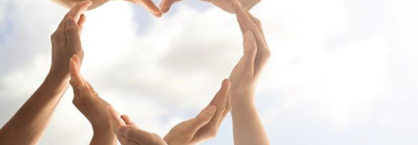 Manos en forma de corazón con el cielo de fondo