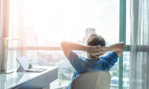 A person sitting in an office chair leaning back and looking out of a window.