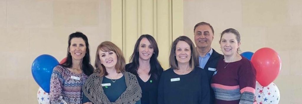 Blue FCU leadership standing next to balloons