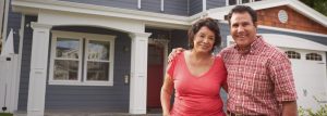 Older couple smiling in front of house