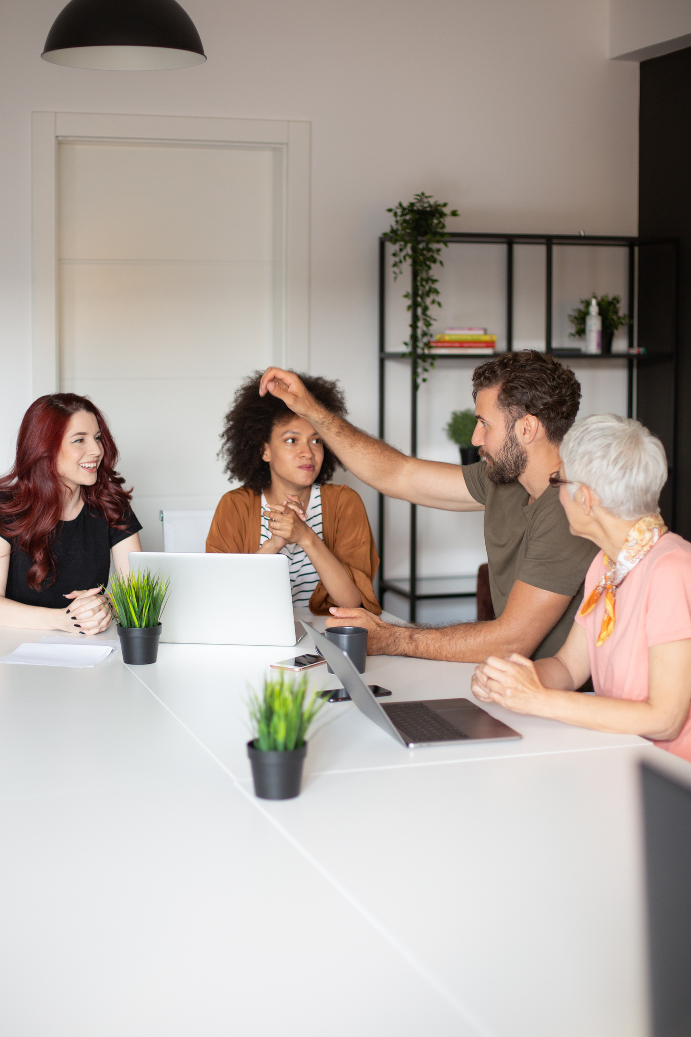 Un empresario vestido de manera informal, sentado en la sala de juntas con sus colegas y participando en una lluvia de ideas.