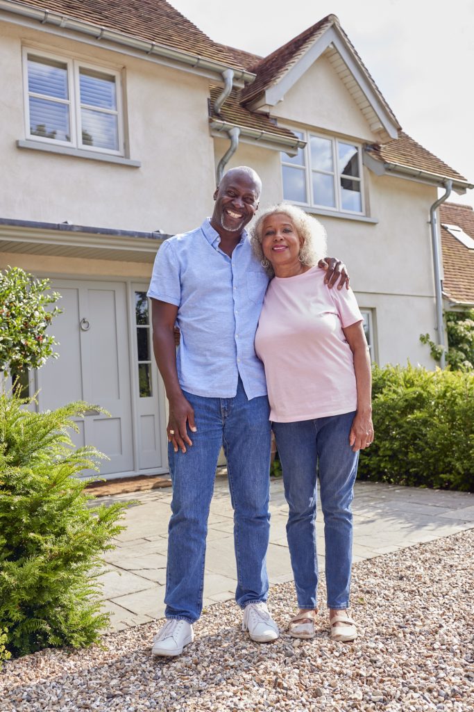 Portrait Of Smiling Senior Couple Standing Outside Home Together